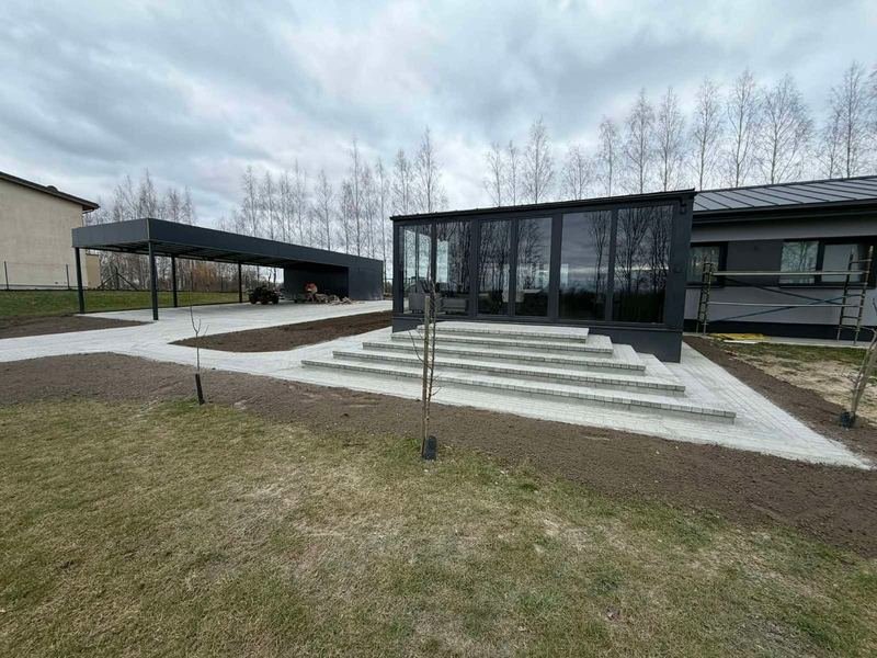 Trinkelėmis išklota aikštelė ir laiptai prie modernaus verslo pastato