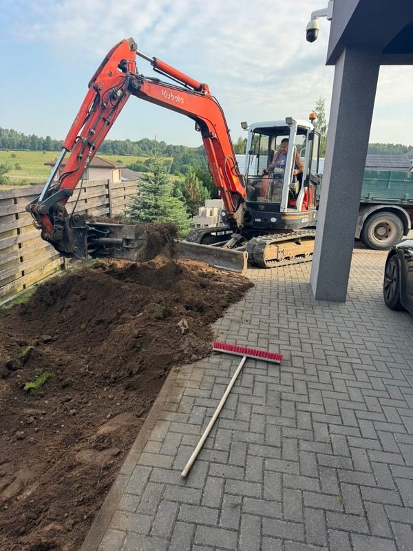 Mini ekskavatoriaus darbai prie išklotos trinkelių dangos
